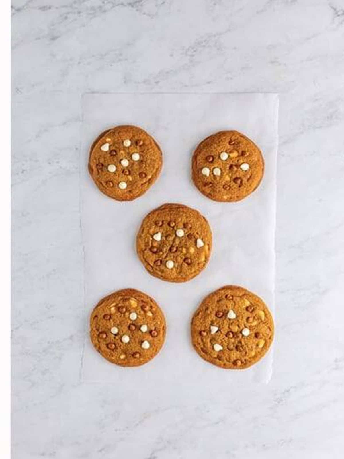 Soft baked gingerbread cookies with chips on a sheet tray.