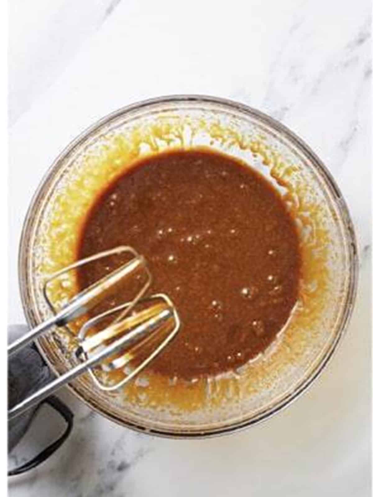 Beating brown sugar, molasses, egg, and vanilla into the butter for gingerbread dough.