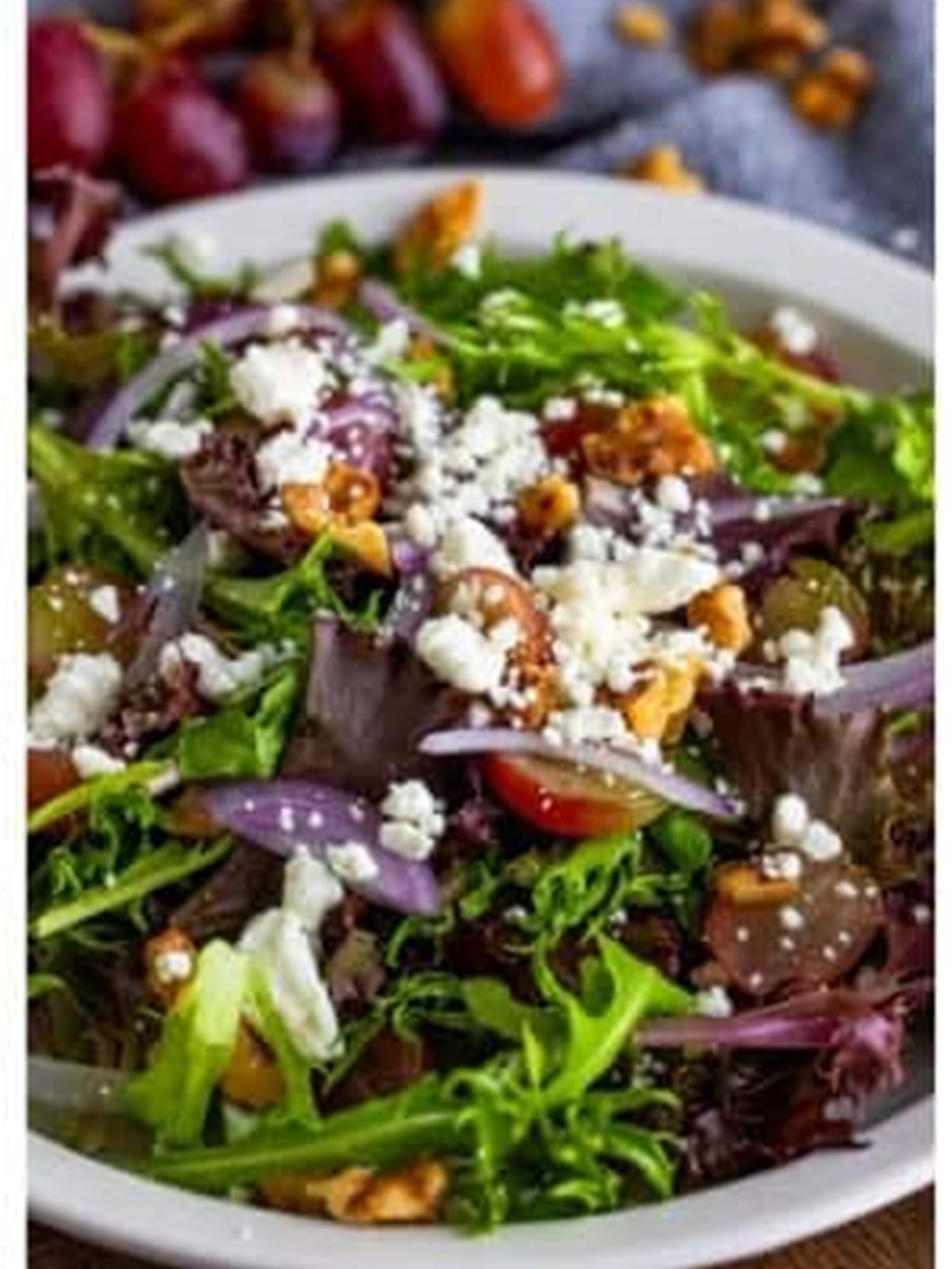 Goat cheese salad topped with grapes, crumbled goat cheese, red onion, and walnuts.