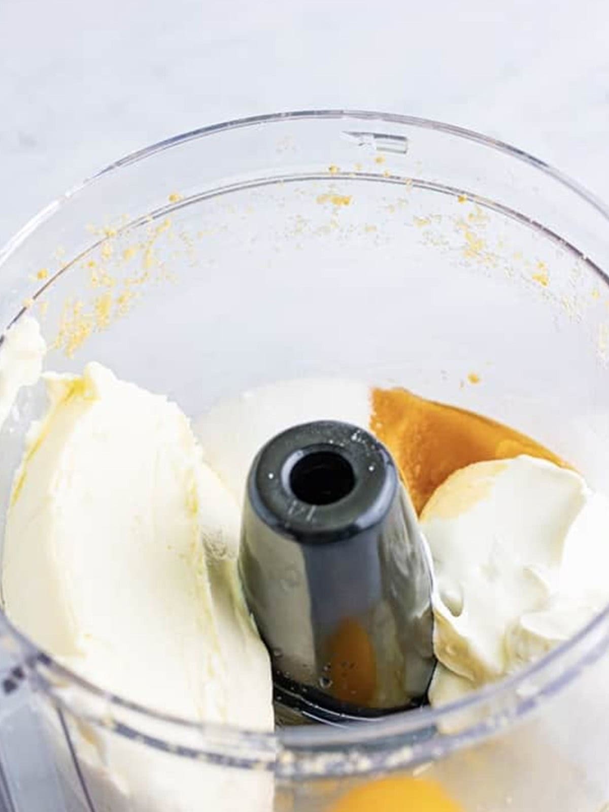 Cream cheese, sugar, sour cream, egg, and vanilla blended in a food processor for the cheesecake filling.