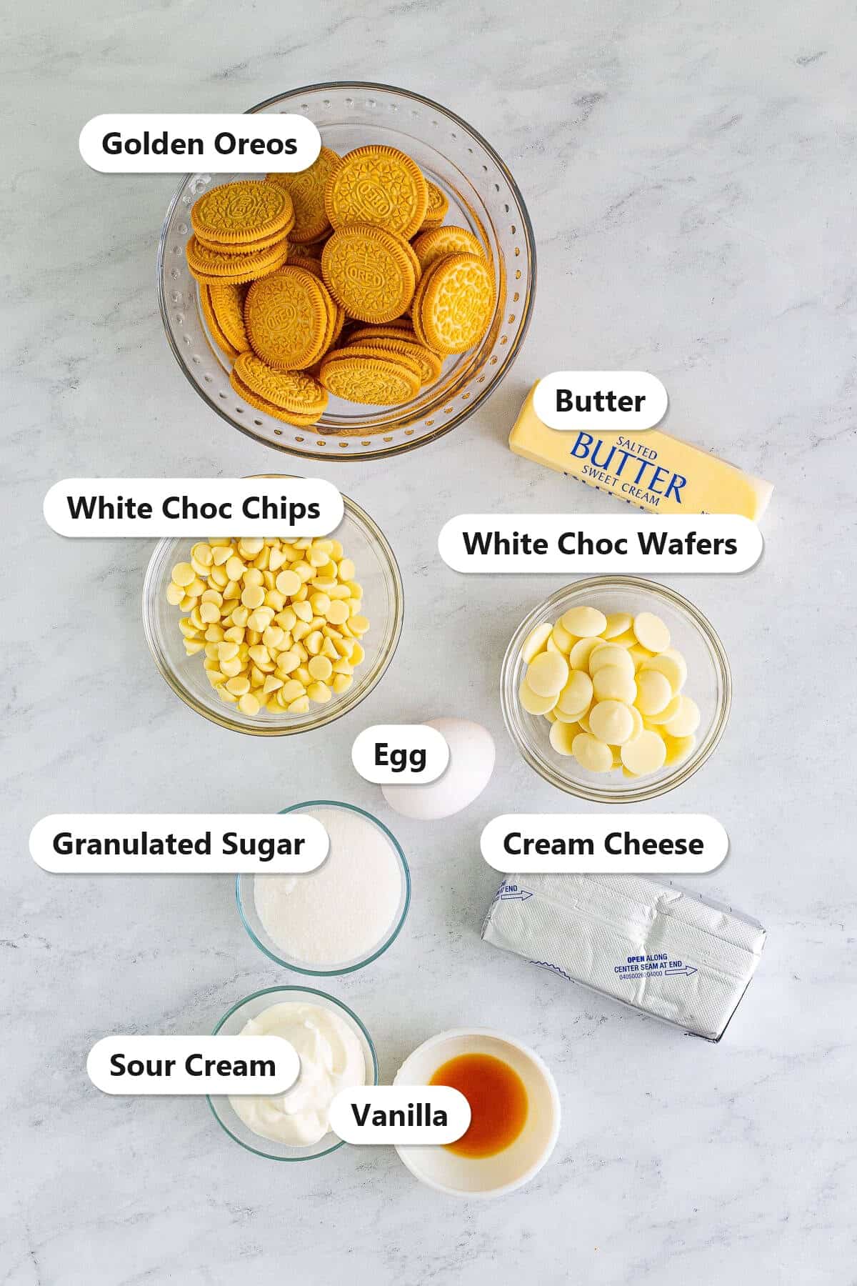 Labeled golden Oreo cheesecake bars ingredients including Golden Oreos, butter, cream cheese, sugar, sour cream, egg, vanilla, and white chocolate.