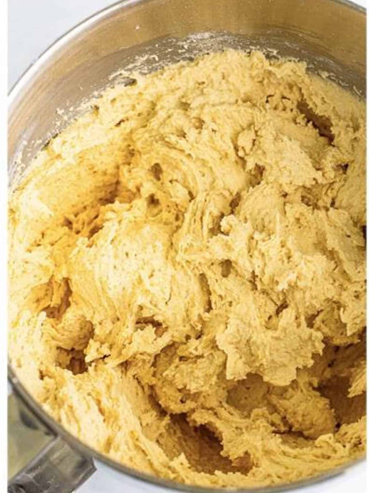 Golden Oreo cookie dough mixed in a stand mixer.