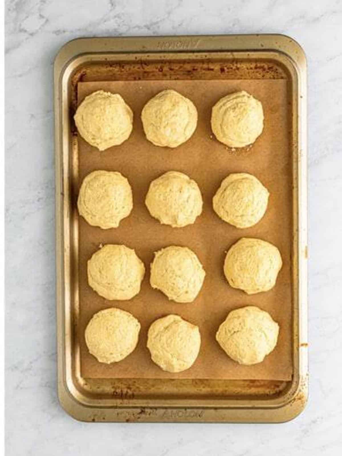 Golden Oreo cookie dough portioned into balls on a baking tray.