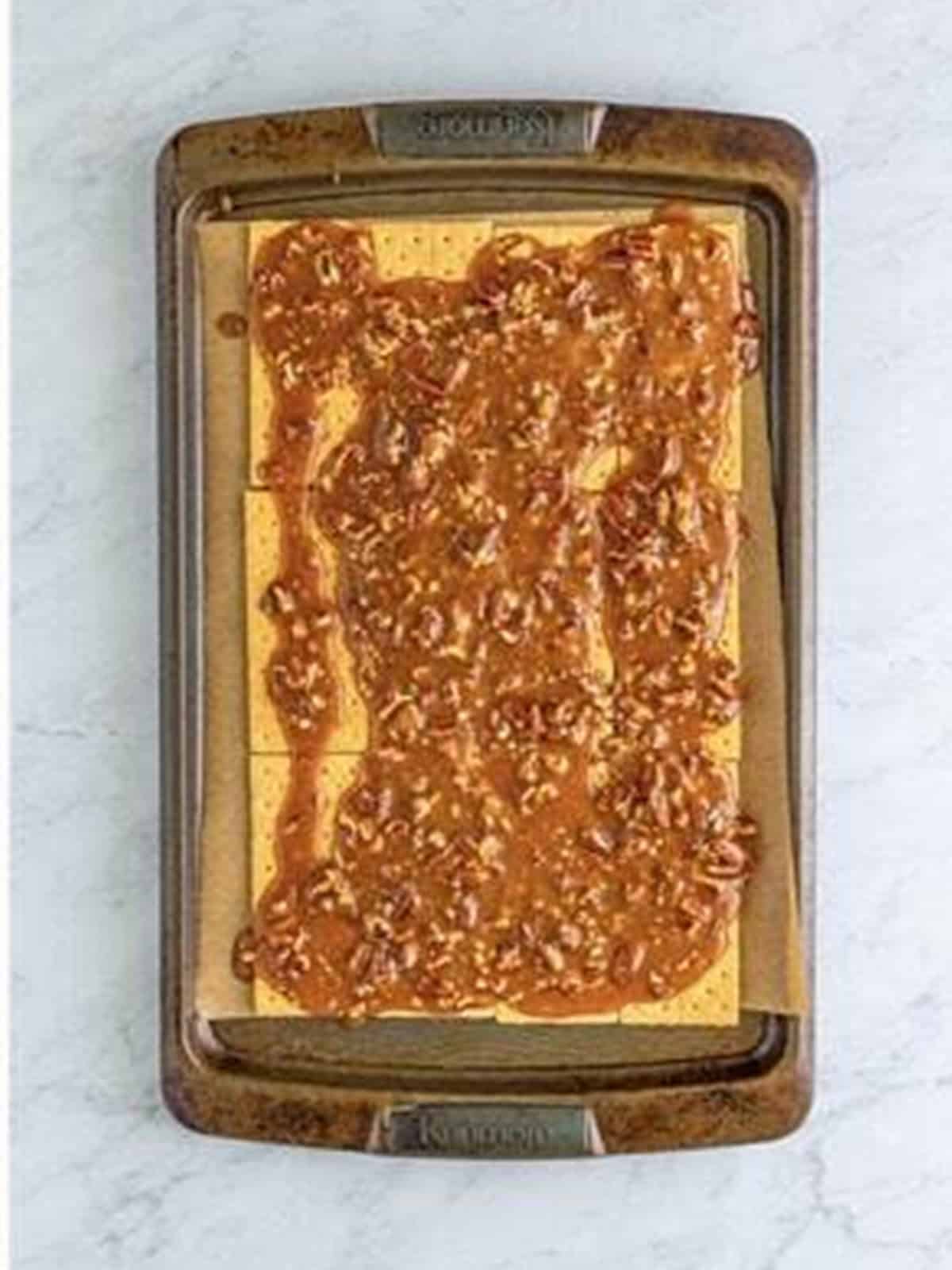 Pecan caramel poured over a tray of graham crackers.