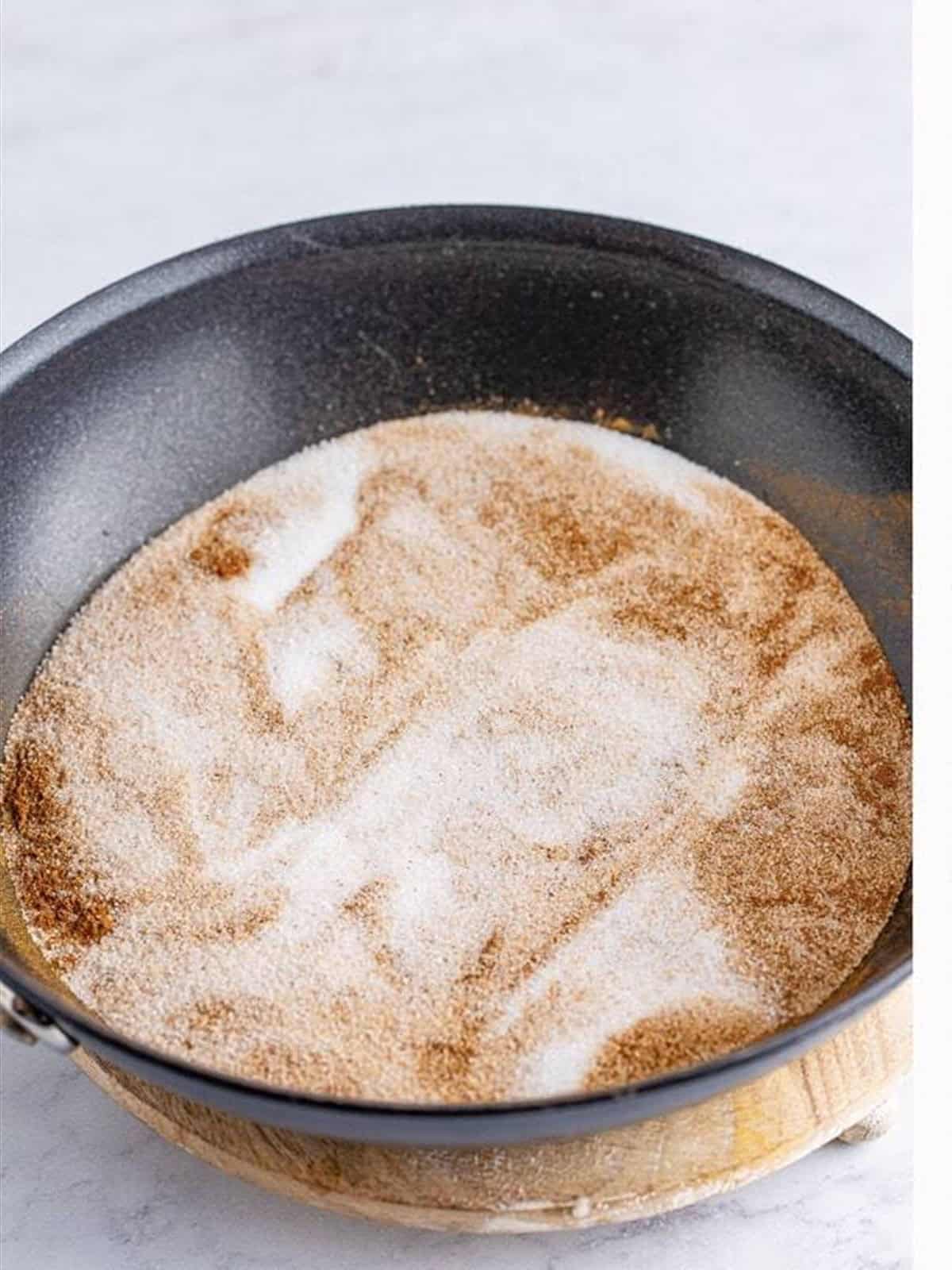 Pecans, sugar, water, cinnamon, and vanilla added to a skillet to make candied pecans.