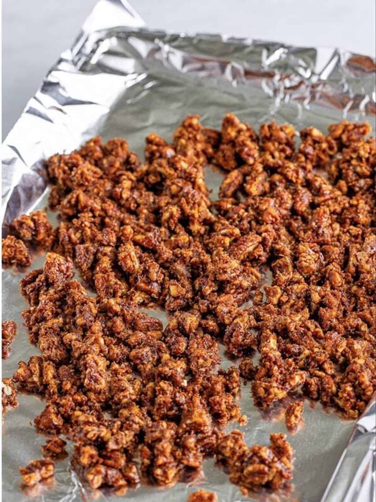 Candied pecans spread on foil to harden.