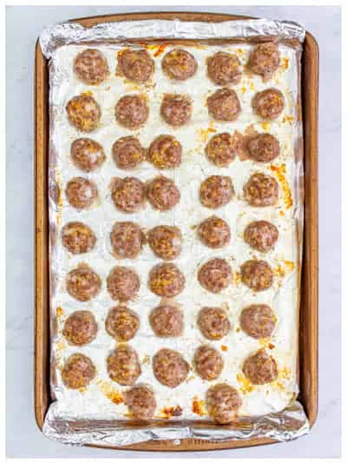 Baked golden meatballs on a sheet tray for grape jelly meatballs.