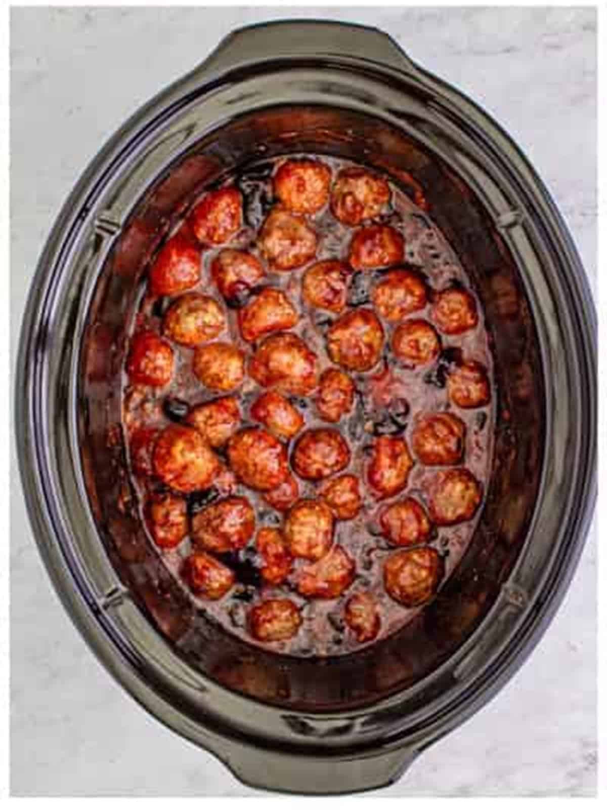 Stirring grape jelly meatballs to coat in the sauce.