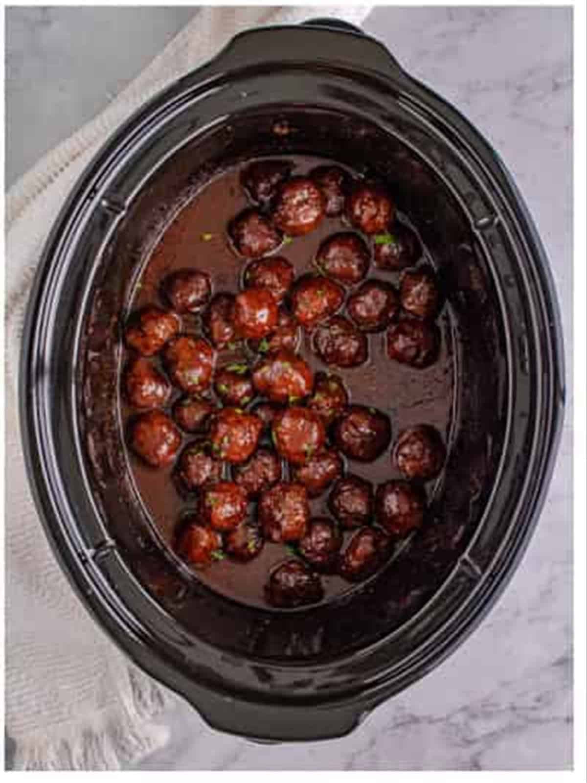 Finished glossy grape jelly meatballs in the slow cooker.
