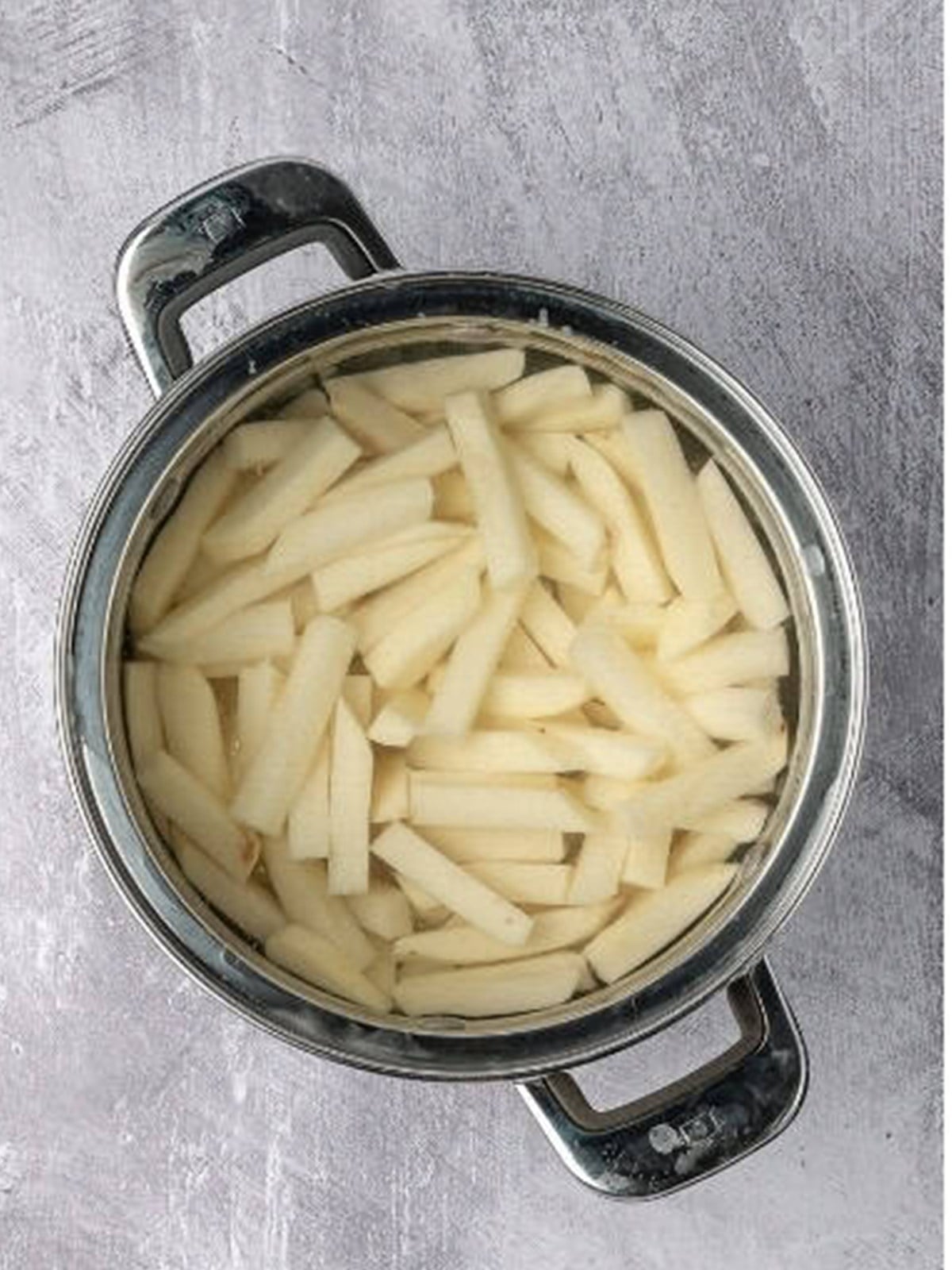Boiling potato fries in a pot of salted vinegar water.