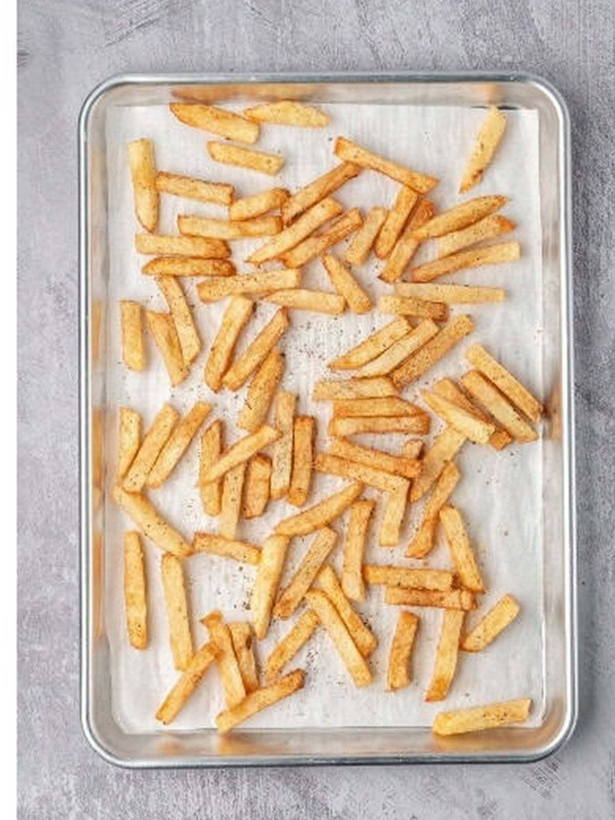 Golden baked fries on a sheet pan for greek fries.