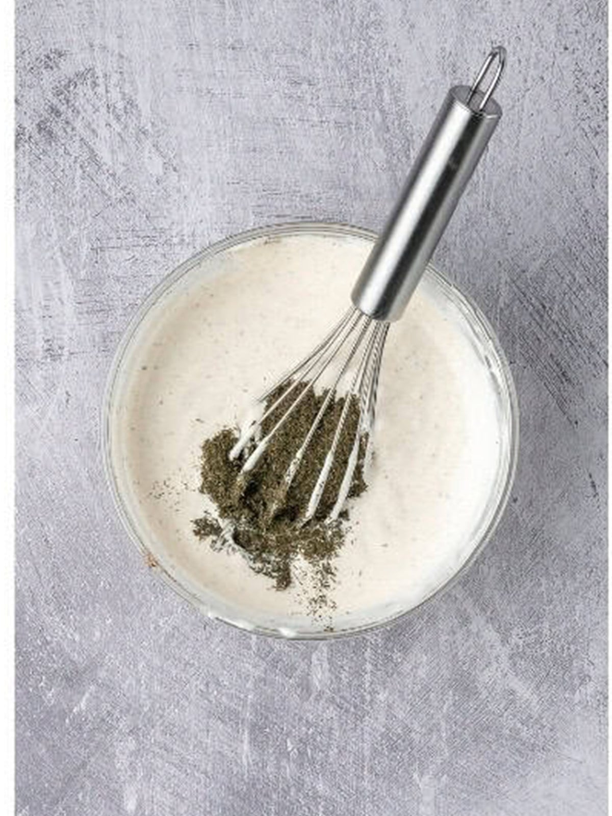 Whisking the creamy dill sauce in a bowl.