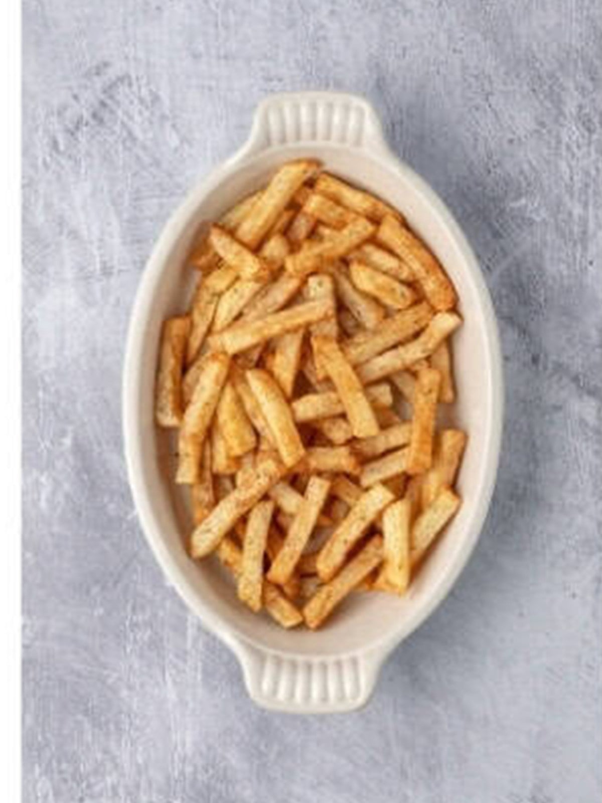 Baked fries layered in an oval serving dish.