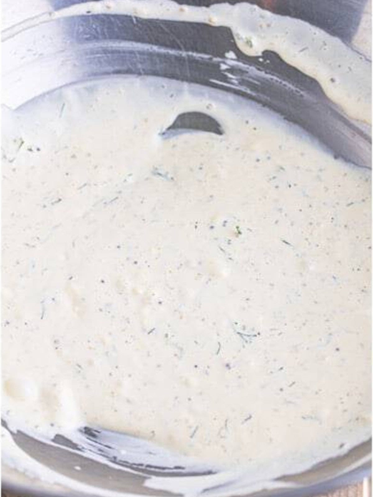 Creamy dressing for Greek Pasta Salad whisked smooth in a metal bowl.
