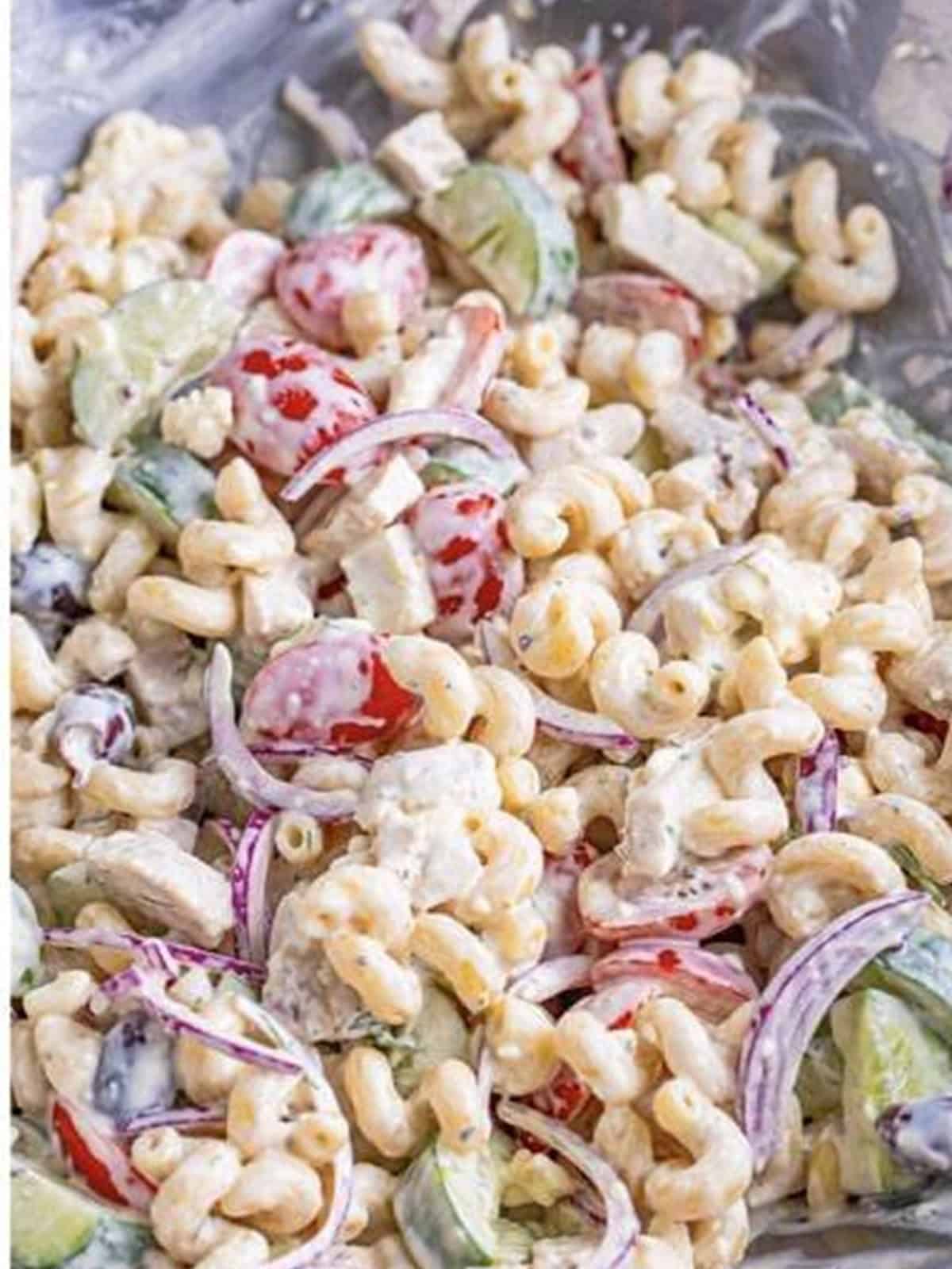 Greek Pasta Salad stirred together in a metal bowl ready to serve.