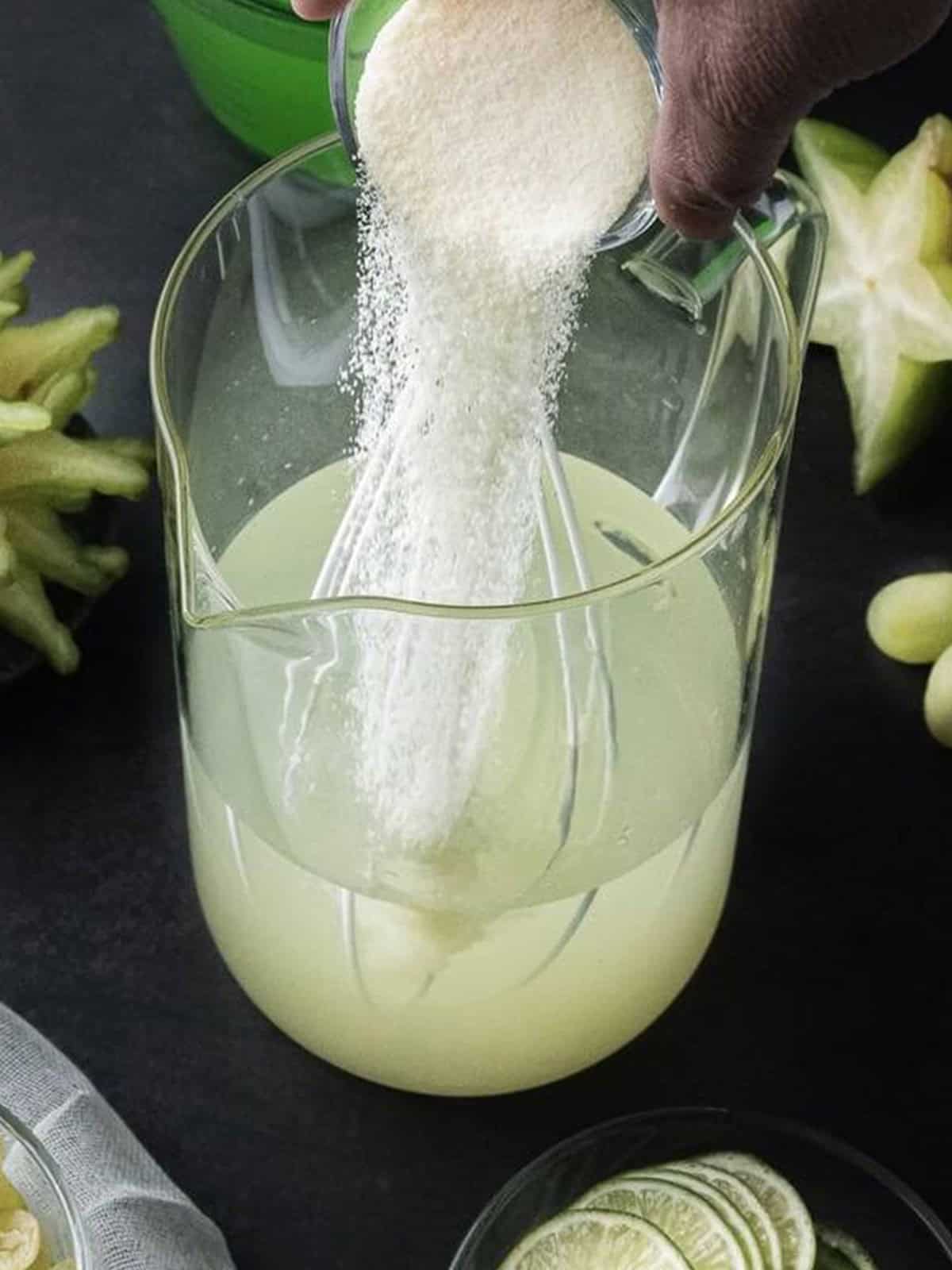 Country Time lemonade powder being whisked into water in a pitcher for green punch.