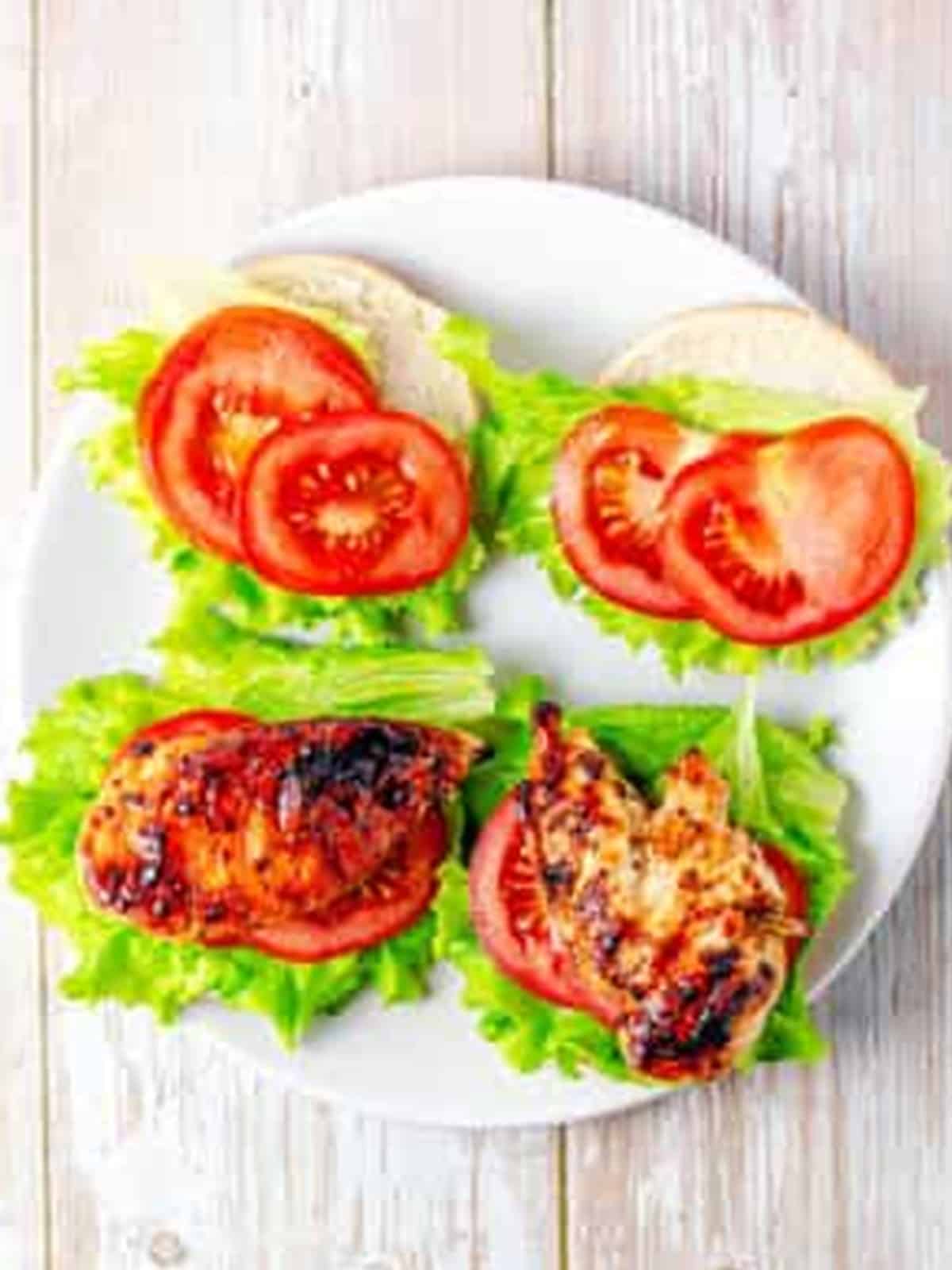Layering lettuce, tomato, and grilled chicken to build the Grilled Chicken Sandwich.