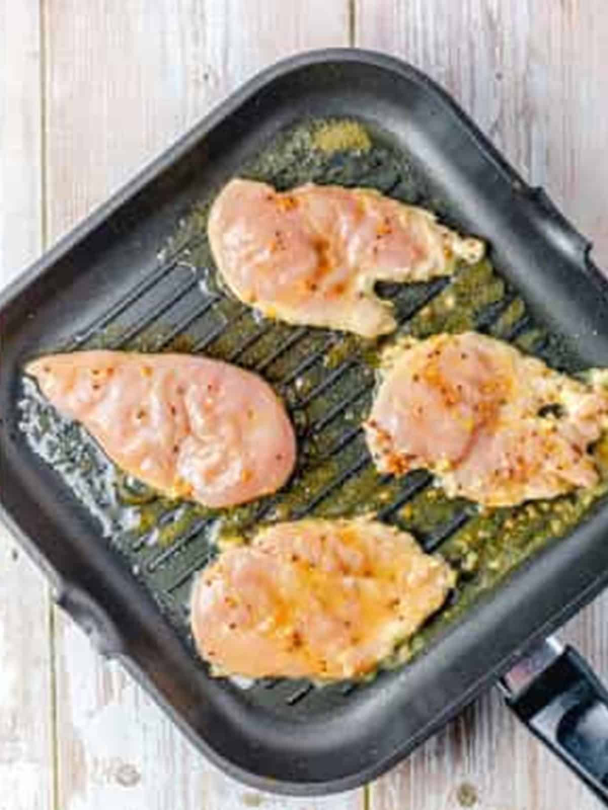 Grilling the marinated chicken on a grill pan for a Grilled Chicken Sandwich.