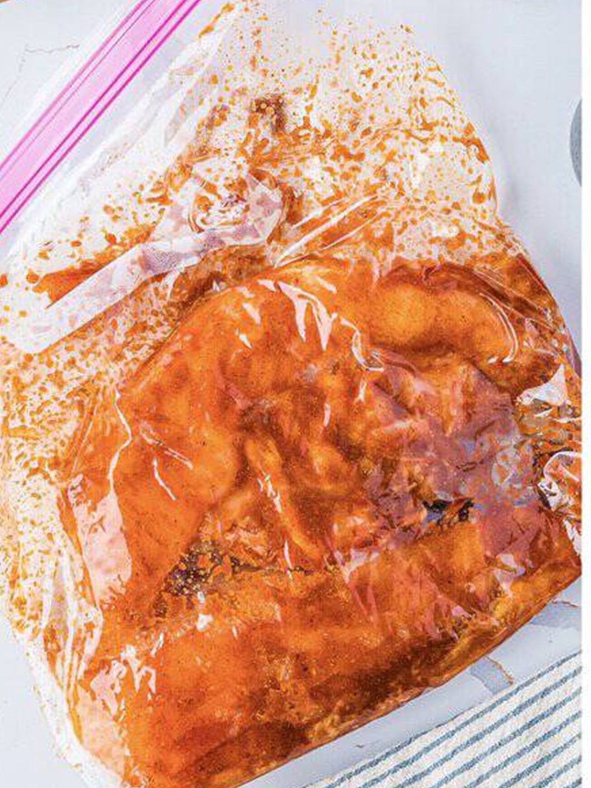 Chicken breasts coated in marinade inside a zip top bag.