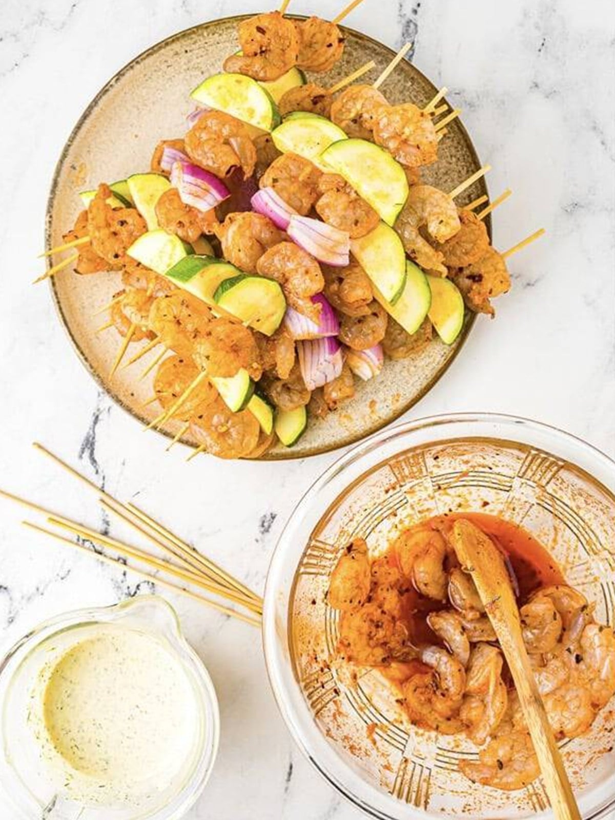 Assembled shrimp skewers with zucchini and red onion before grilling.