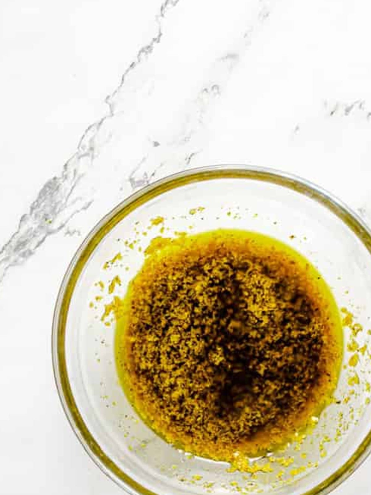 Pesto and olive oil marinade whisked together in a glass bowl for grilled vegetable skewers.