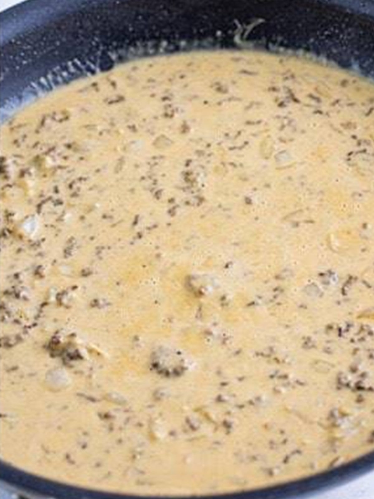 A creamy beef stock and cream sauce in a skillet for ground beef stroganoff.