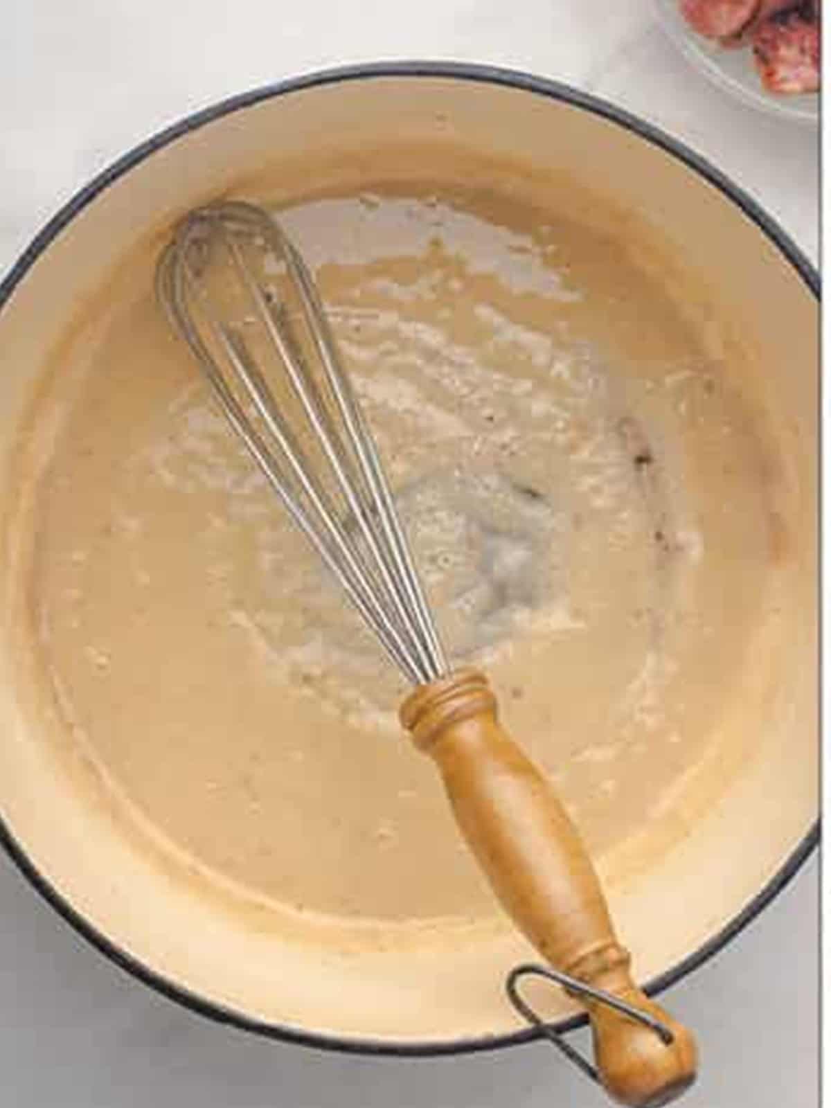 Whisking oil and flour into a roux in a pot to make gumbo.