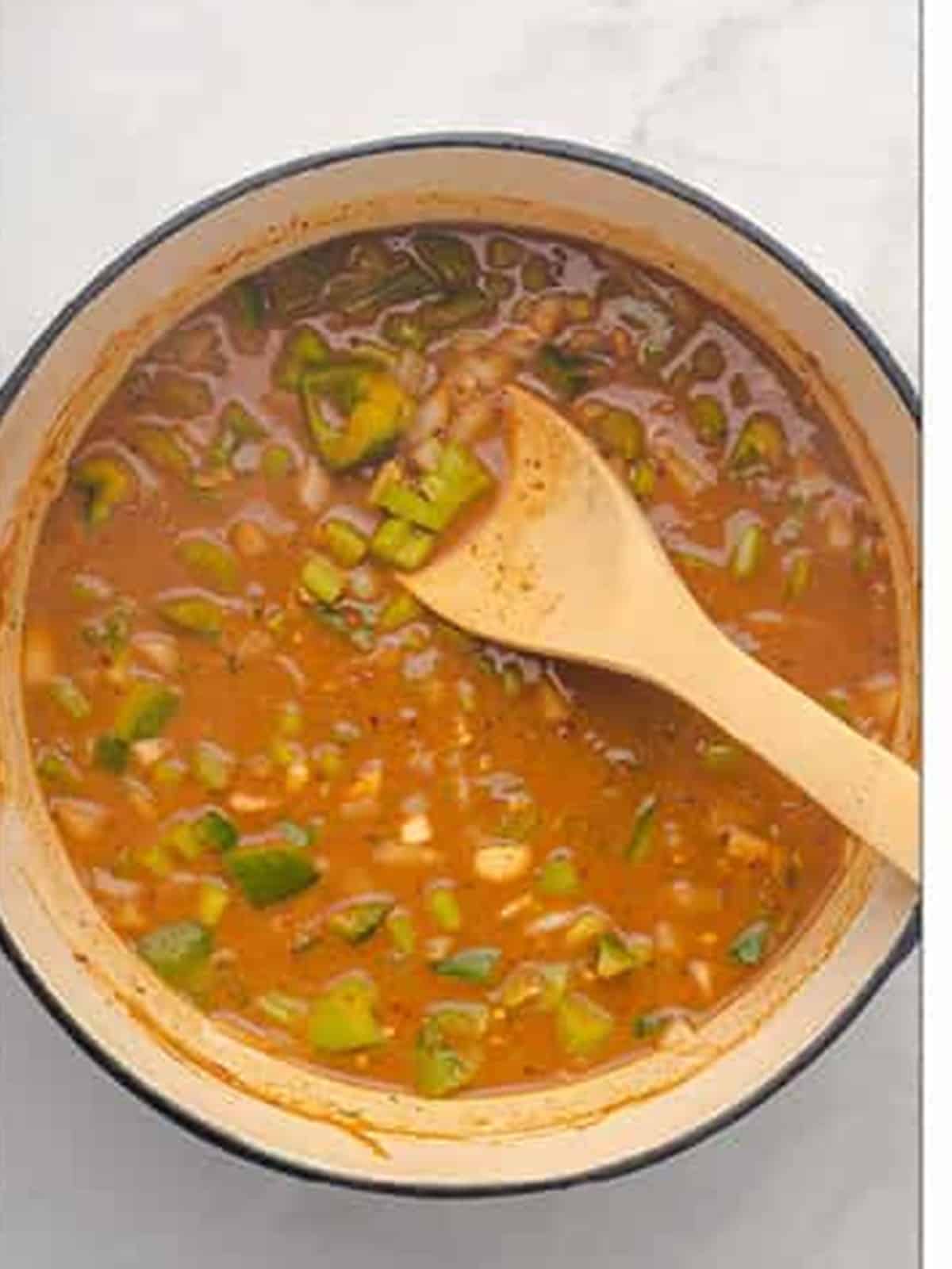 Chicken broth and Cajun seasoning simmering with the roux and vegetables for gumbo.