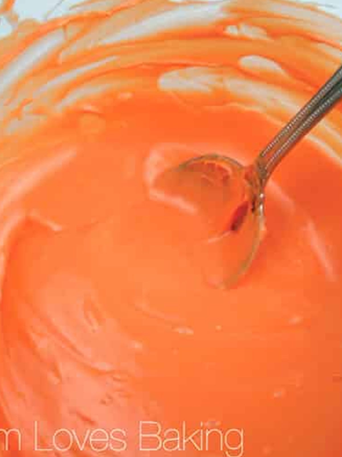 Melted orange candy in a bowl for dipping halloween chocolate covered strawberries.