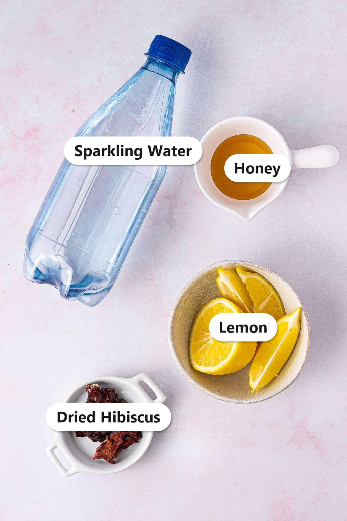 Labeled ingredients for hibiscus tea including dried hibiscus flowers, lemon, honey, and sparkling water.