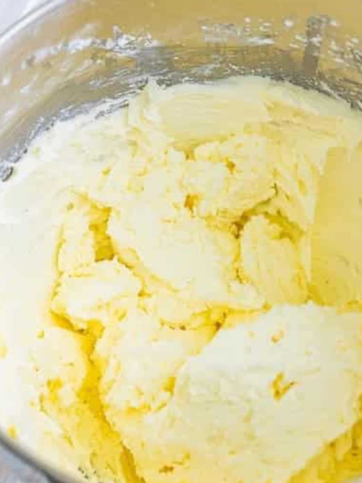 Beating powdered sugar, milk, and vanilla into fluffy buttercream frosting.