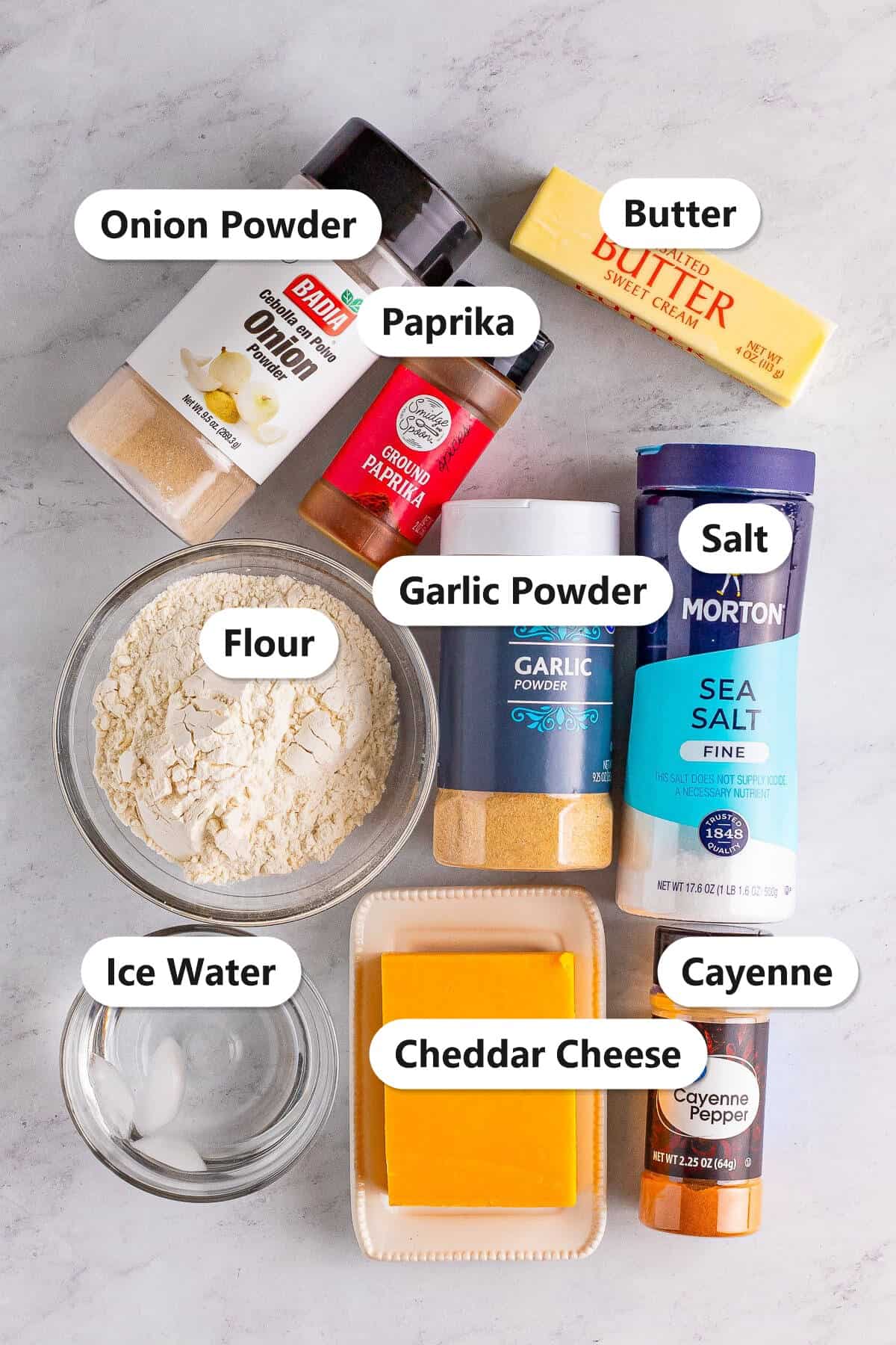 Labeled ingredients for homemade Cheez-Its including cheddar cheese, flour, butter, garlic powder, onion powder, paprika, cayenne, salt, and ice water.