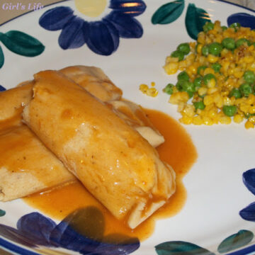 A plate of homemade chicken tamales topped with red sauce.