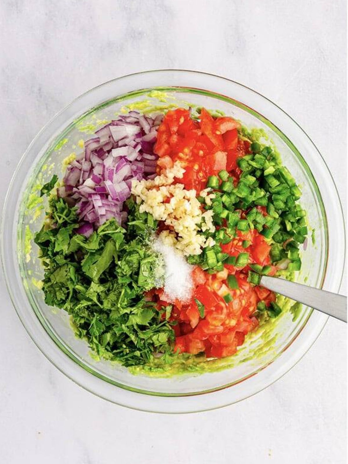 Diced tomato, red onion, jalapeno, and cilantro added to mashed avocado for guacamole.