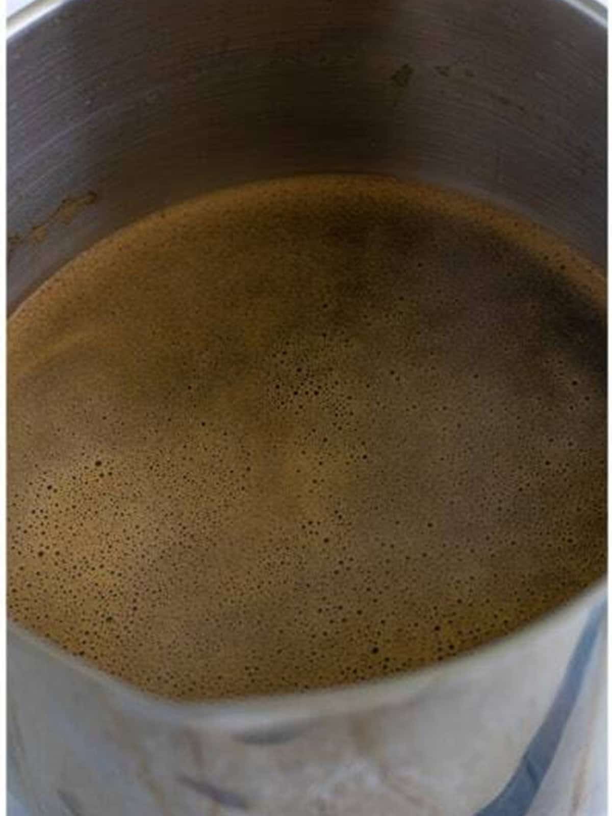 Stirring the white rum and vanilla into the coffee and syrup mixture for homemade Kahlua.