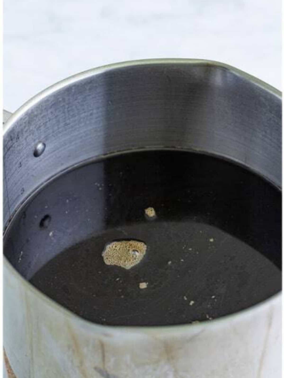 Water and instant coffee combined in a pot for homemade Kahlua.