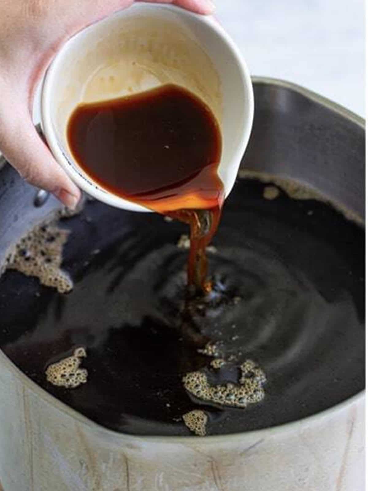 Pouring the cooled coffee into the simple syrup for homemade Kahlua.