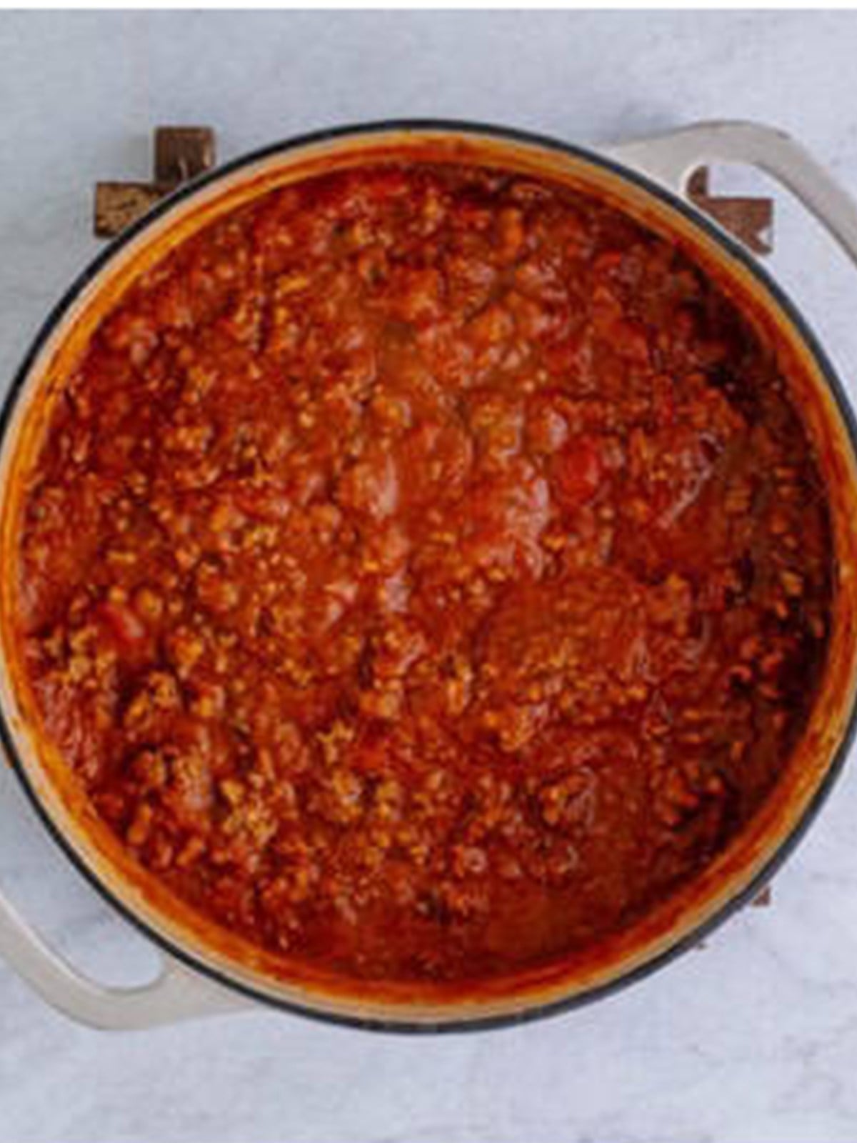 Rich red meat sauce simmering in a pot for homemade lasagna.