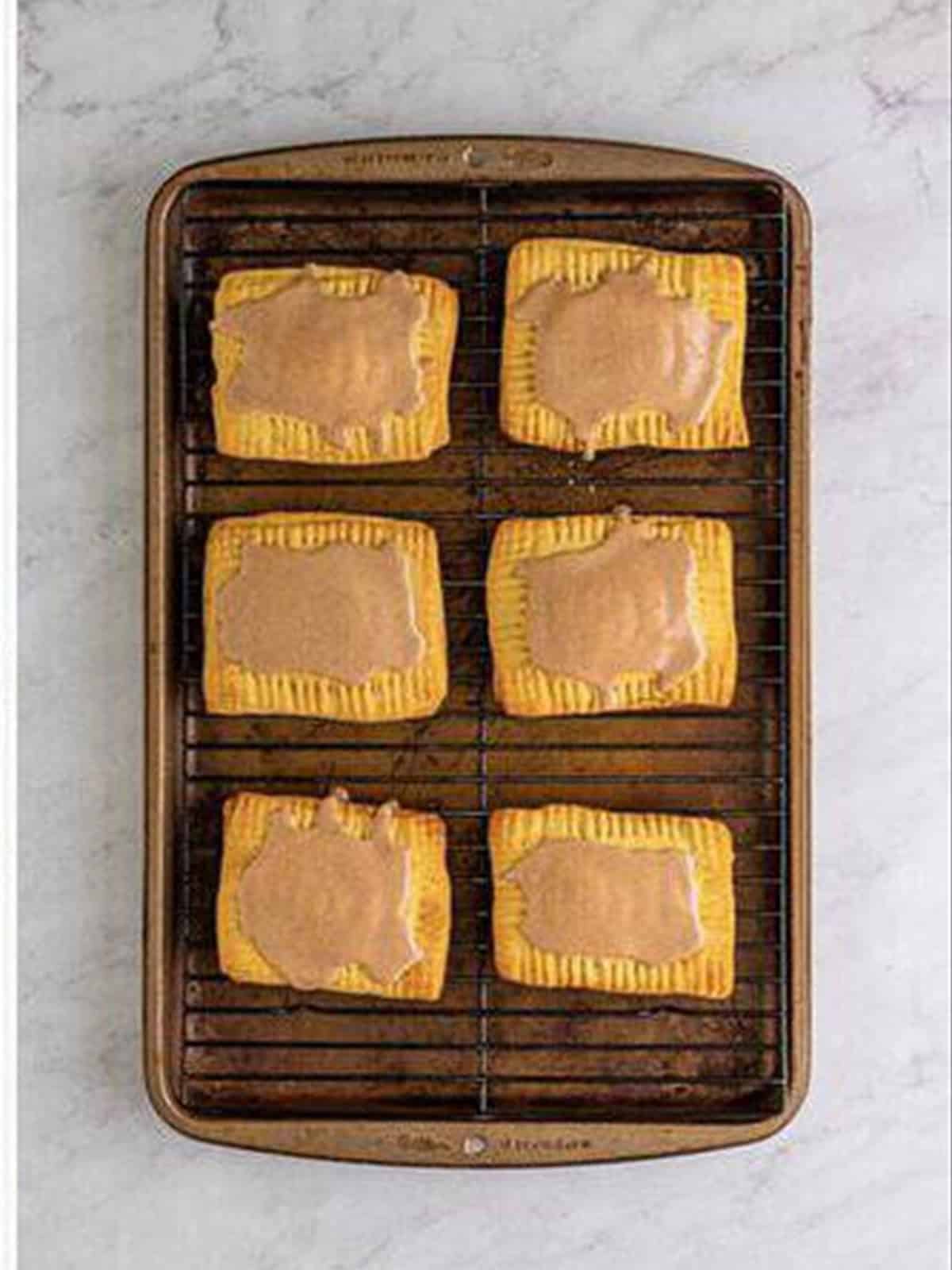 Glazed homemade pop tarts on a baking sheet.