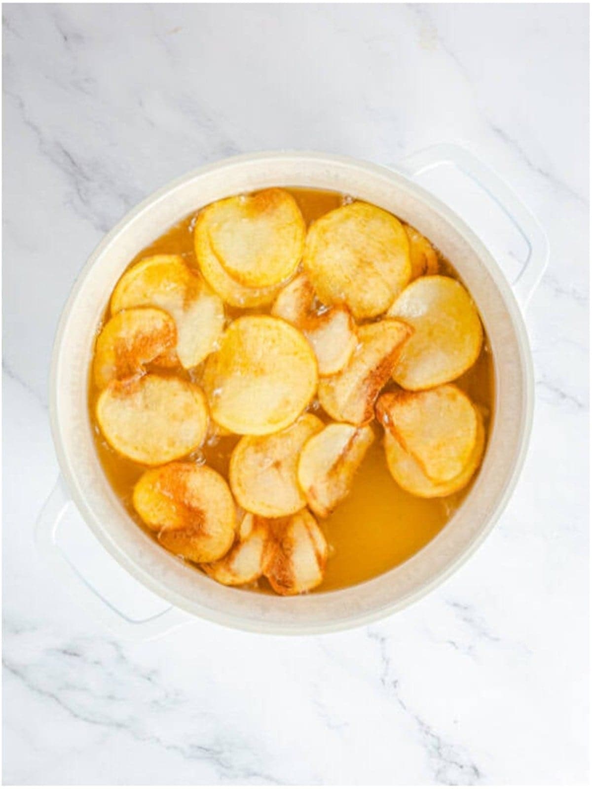 Potato slices frying in hot oil until golden for Homemade Potato Chips.