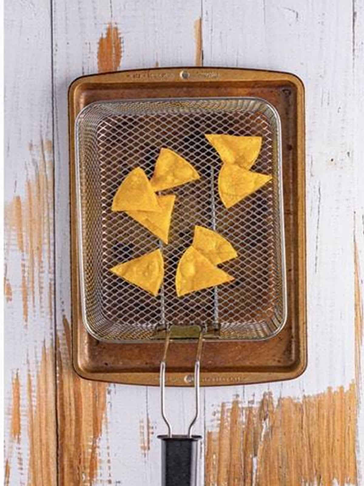 Tortilla triangles frying in hot oil until crisp and golden.