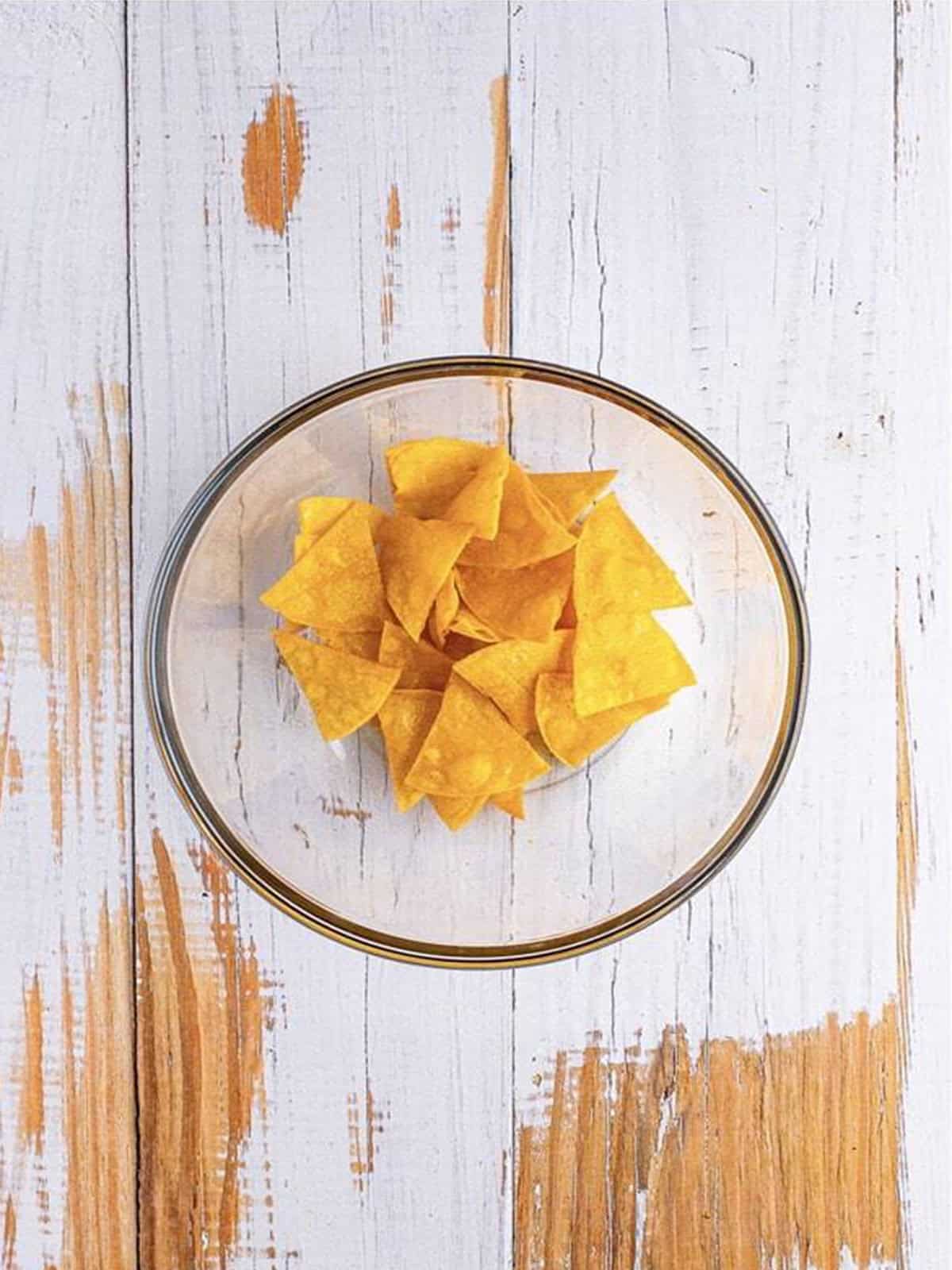 Fried tortilla chips tossed with salt in a bowl.