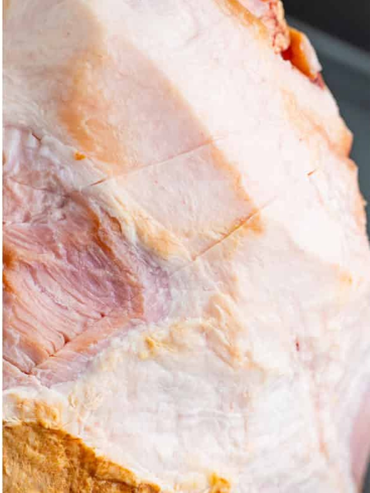 A smoked ham scored in a diamond pattern on a foil rack before glazing.