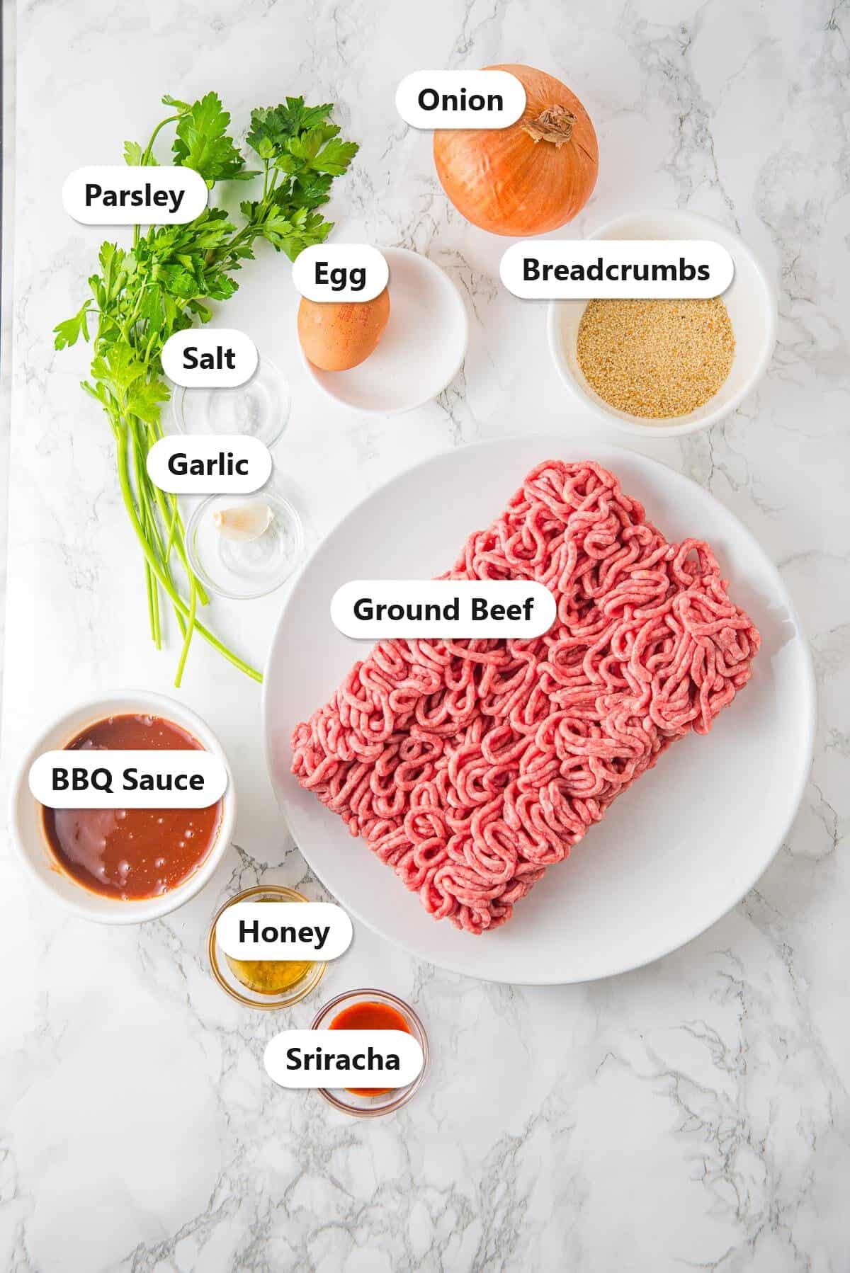 Labeled ingredients for oven honey BBQ meatballs including ground beef, egg, breadcrumbs, onion, garlic, parsley, salt, BBQ sauce, honey, and Sriracha.
