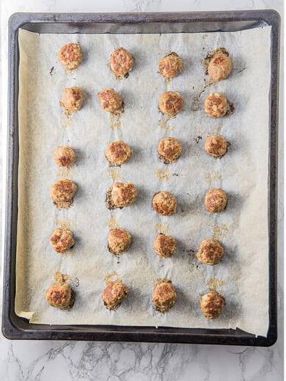 Baked honey BBQ meatballs browned on the baking sheet.