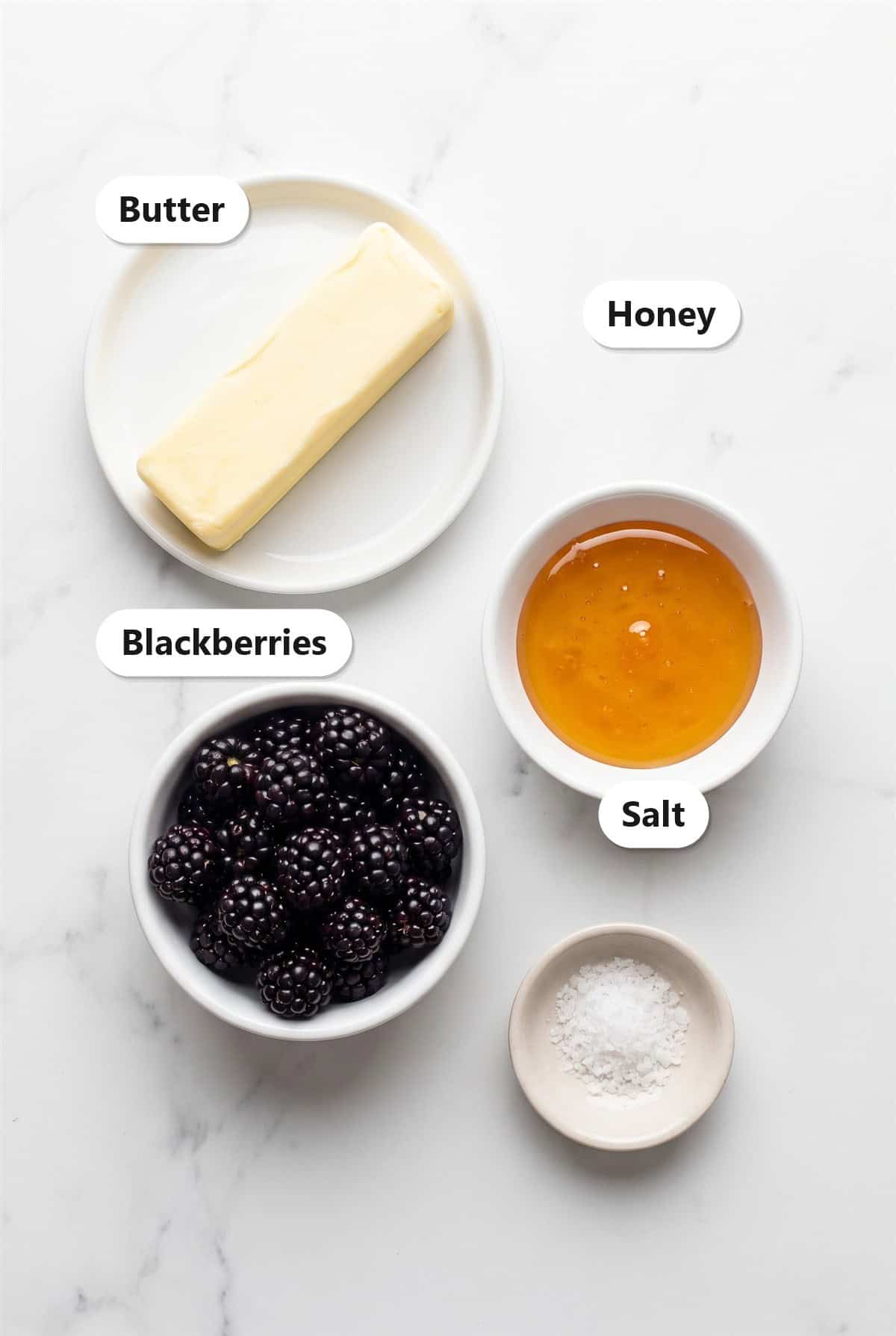 Ingredients to make whipped honey butter including softened butter, fresh blackberries, honey, and salt.