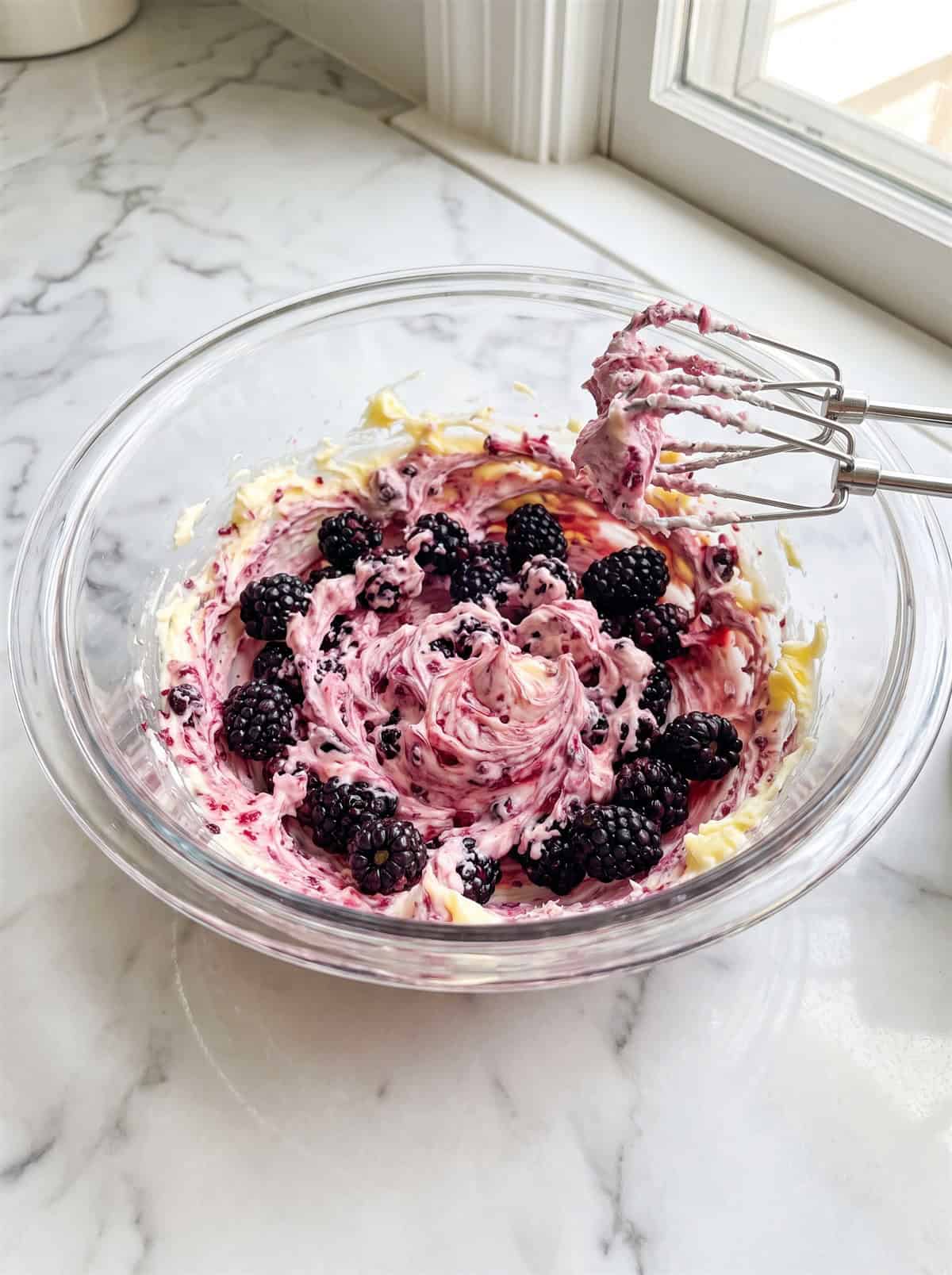 Butter and blackberries partially whipped into a streaky pink honey butter with mixer beaters.