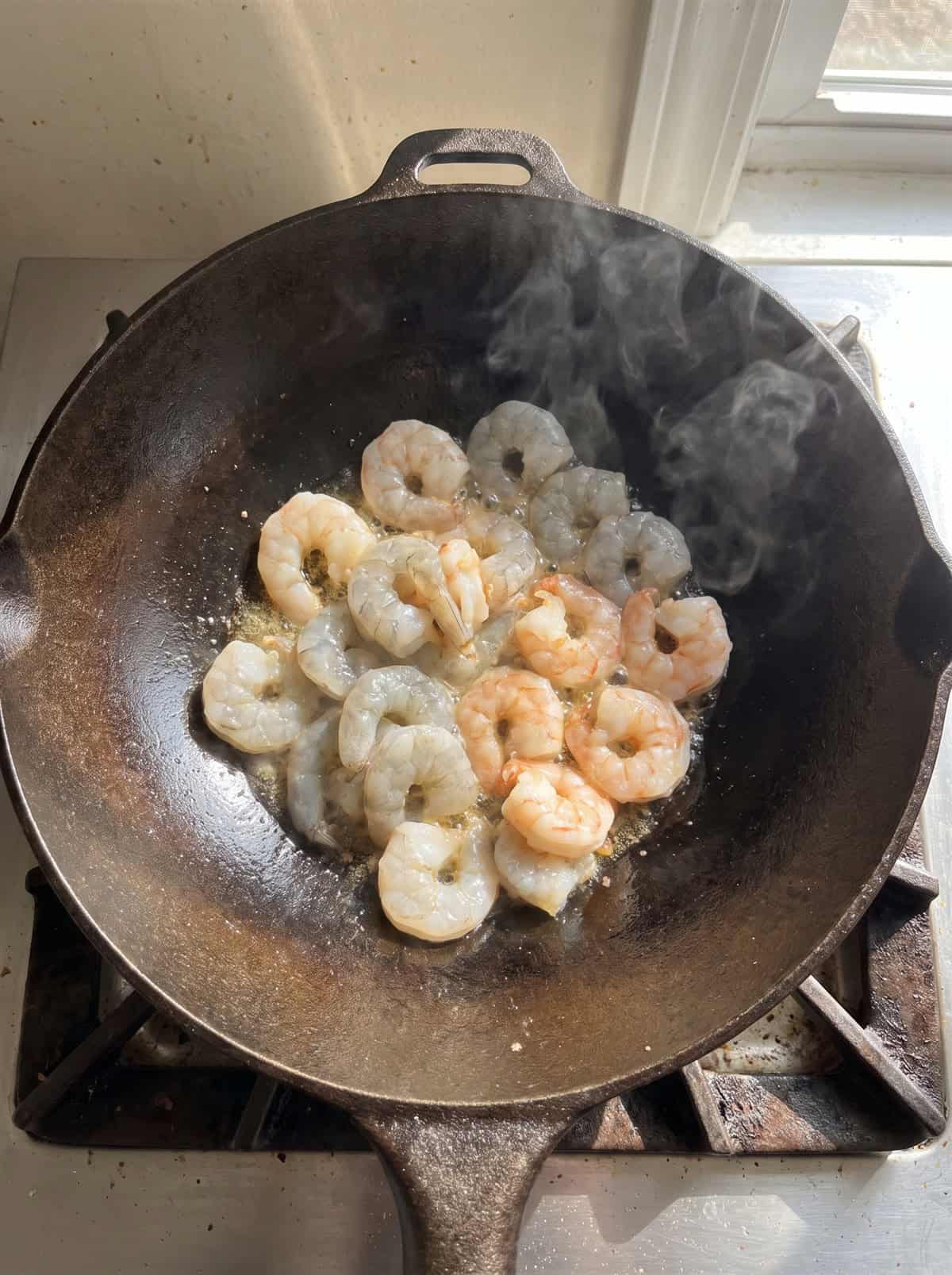 Shrimp searing in a wok until pink.