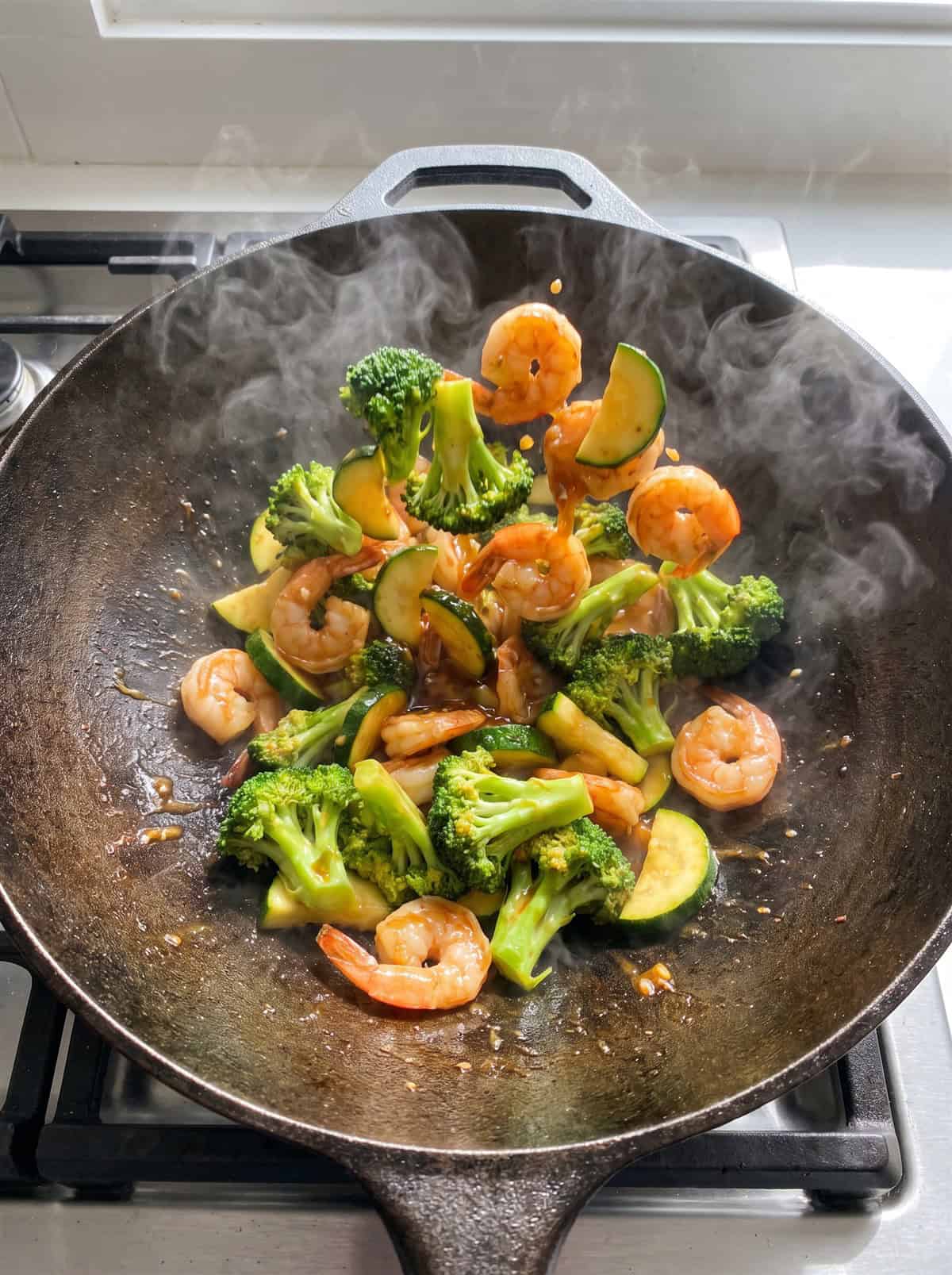 Shrimp, broccoli, and zucchini tossed with honey garlic sauce in a wok.