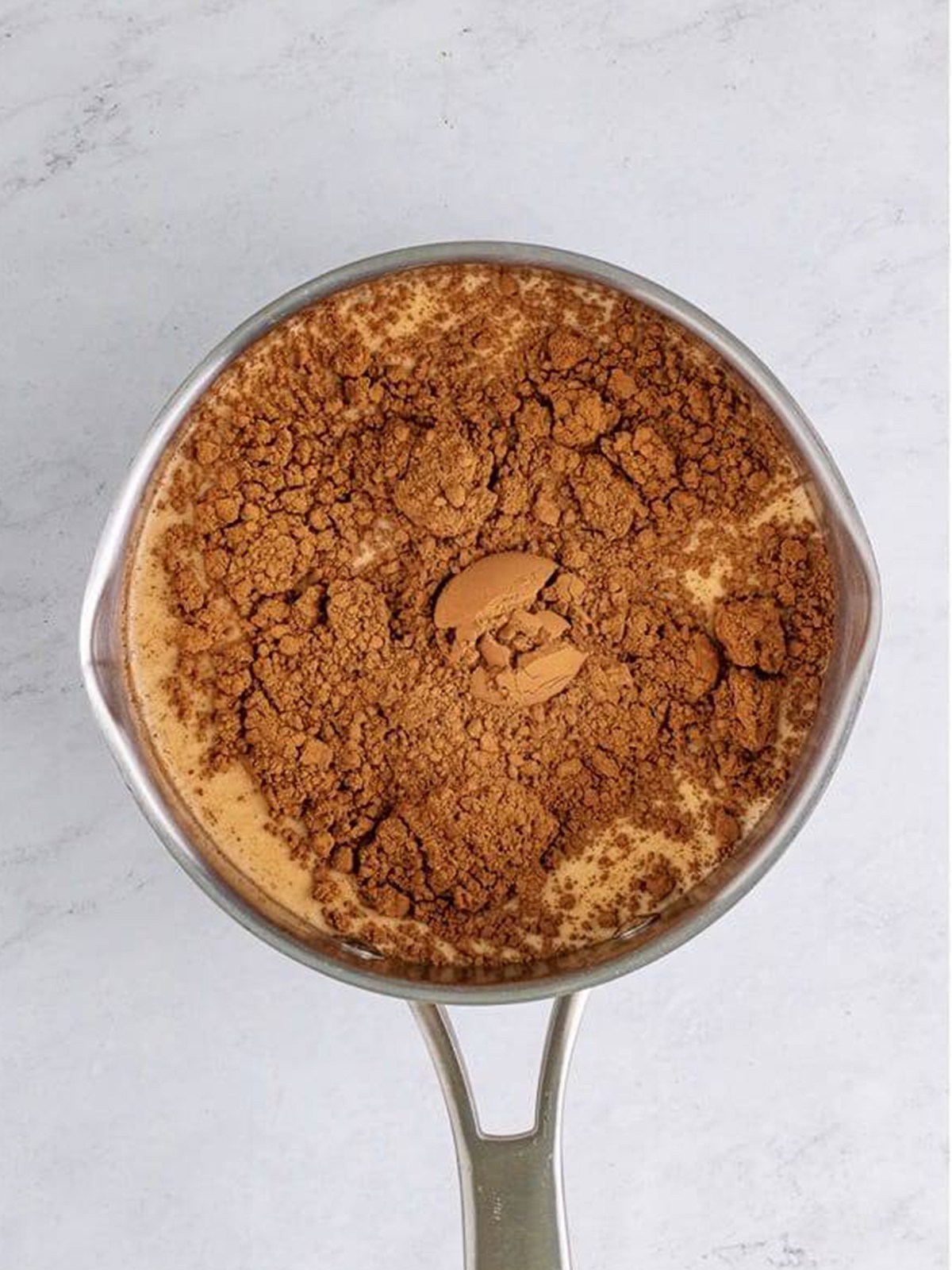 Whole milk, heavy cream, cocoa powder, and sugar combined in a saucepan to make hot chocolate.